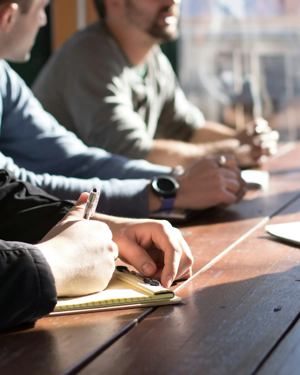 Reunión de trabajo alrededor de una mesa, tomando notas